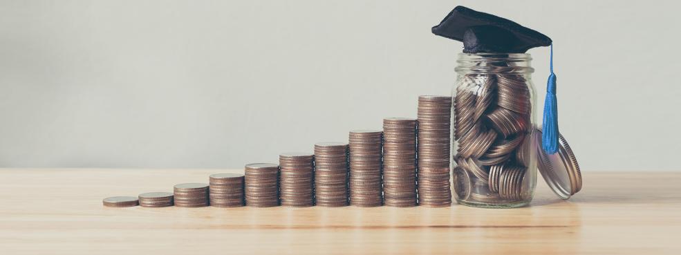 coins stacked in row with grad cap